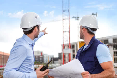 Bauwesenversicherung - Bauleiter und Bauarbeiter vor Baustelle