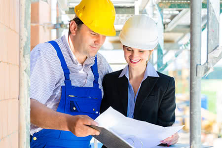 Bauherrenhaftpflichtversicherung - Bauherrin mit einem Bauarbeiter auf der Baustelle