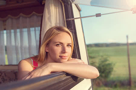 Wohnwagen Versicherung - Frau schaut aus dem Wohnwagen Fenster