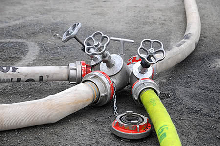 versicherungscheck24.de – Feuerwehrschläuche liegen einsatzbereit am Boden