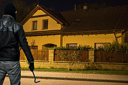 versicherungscheck24.de – Hausratversicherung – Raub – Einbrecher steht vor Einfamilienhaus