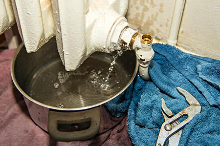 versicherungscheck24.de – Hausratversicherung – wichtig – Eimer unter tropfender kaputter Heizung