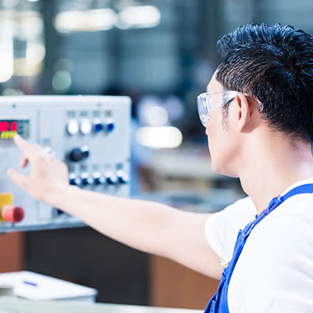 versicherungscheck24.de – Maschinenversicherung – Junger Arbeiter bedient Maschine