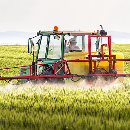 versicherungscheck24.de – Landwirtschaftsmaschine besprüht Getreide auf Feld