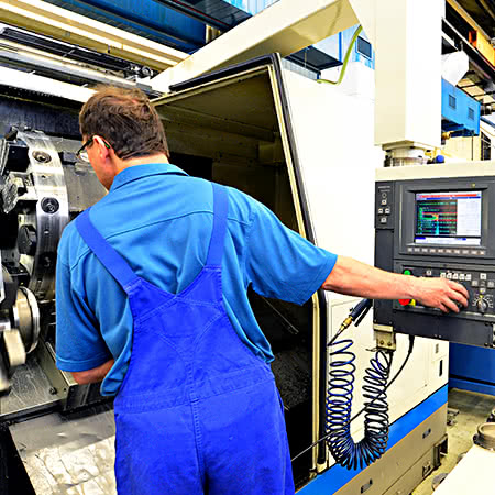 versicherungscheck24.de – Maschinenversicherung Motorschaden – Arbeiter an CNC-Maschine