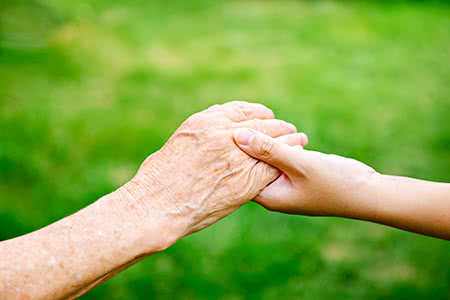 versicherungscheck24.de – Pflegeversicherung für Eltern – Junge Hand hält alte Hand