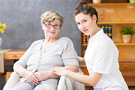 versicherungscheck24.de – Soziale Pflegeversicherung – Seniorin mit freundlicher Pflegekraft