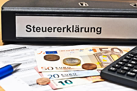 versicherungscheck24.de – Pflegeversicherung – Vorversicherungszeit – Ordner Steuererklärung und Geld auf Schreibtisch