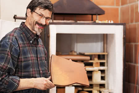 Betriebshaftpflicht Ofenbauer und Luftheizungsbauer - Mann mit einer Ofen Ziegel ind der Hand