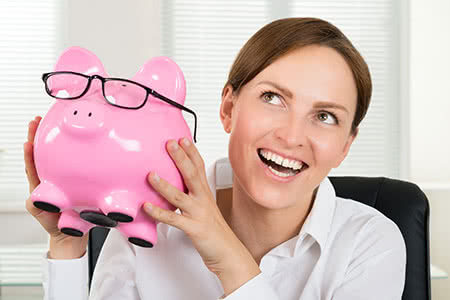 Gewerbehaftpflichtversicherung - Glückliche Geschäftsfrau mit einem Sparschwein