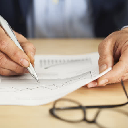 Grundfähigkeitsversicherung Kosten - Mann rechnet Kosten anhand eines Diagrammes aus