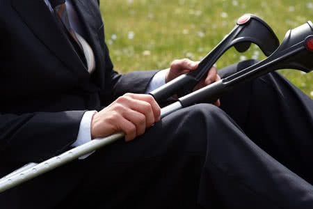 Die Erwerbsunfähigkeit - das unterschätzte Risiko - Mann im Anzug mit Krücken in der Hand