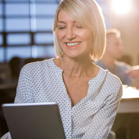 Riester Rente Vergleich - Lächelnde Frau mit einem Tablet