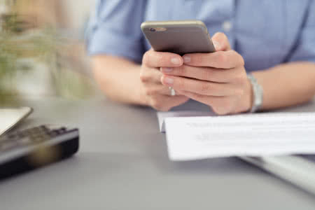 Risikolebensversicherung Kosten - Frau mit einem Handy mit Unterlagen