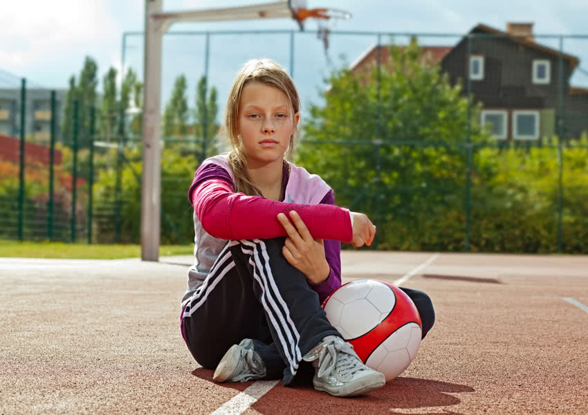 Unfallversicherung - Mädchen mit einem Gibs auf dem Sportplatz