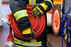 versicherungscheck24.de – Feuerrohbauversicherung Bedingungen – Feuerwehrmann hält gewickelten Schlauch in den Händen