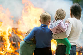 versicherungscheck24.de – Feuerrohbauversicherung Leistungen – Familie schaut sich Flammen und Rauch am Haus an